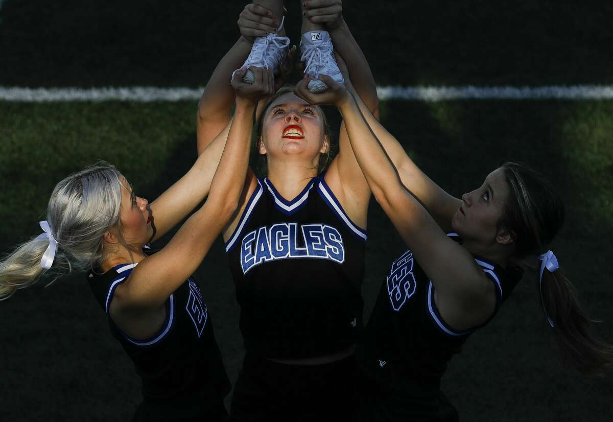 New Caney cheerleader Sierra Kenton, center, helps hold up a teammate before a high school football game at Randall Reed Stadium, Friday, Sept. 3, 2021, in New Caney.