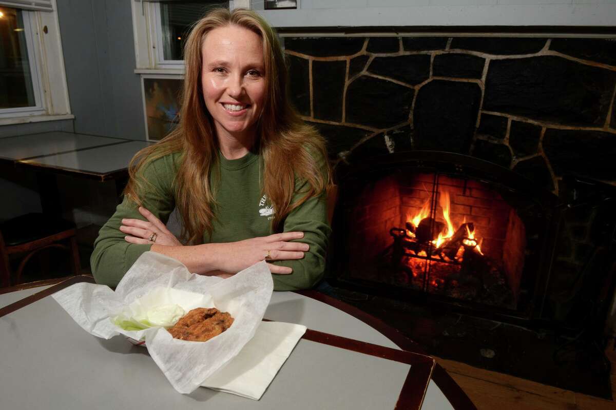 Co-owner Jennifer Cusick poses with a basket of chicken wings at the Windsock Inn, in Stratford, Conn. Nov. 22, 2021.