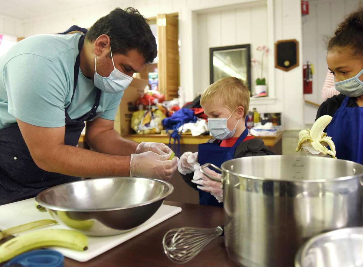 Chef Juan Benitez helps CCI students Daniel Zazula and Makayla Williams make banana bread for Thanksgiving meals at St. Roch Church in the Chickahominy section of Greenwich, Conn. Monday, Nov. 22, 2021. Community Centers Inc. made Thanksgiving meals for 90 seniors, about 50 CCI families, and 20 Kids in Crisis families. Chef Juan Benitez worked with kids from the CCI program Monday to make banana bread and put the finishing touches on Thanksgiving dinners that will be distributed with the help of volunteers and town officials on Wednesday. Food donations from Stew Leonard’s and Houlihan Lawrence helped the meals come to fruition.