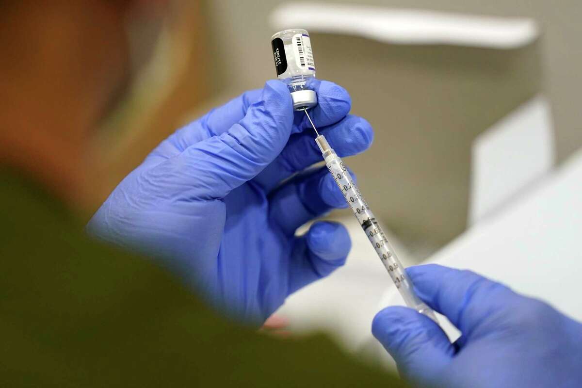 FILE - A healthcare worker fills a syringe with the Pfizer COVID-19 vaccine at Jackson Memorial Hospital on Oct. 5, 2021, in Miami. U.S. regulators have opened up COVID-19 booster shots to all and more adults, Friday, Nov. 19, letting them choose another dose of either the Pfizer or Moderna vaccine. (AP Photo/Lynne Sladky, File)