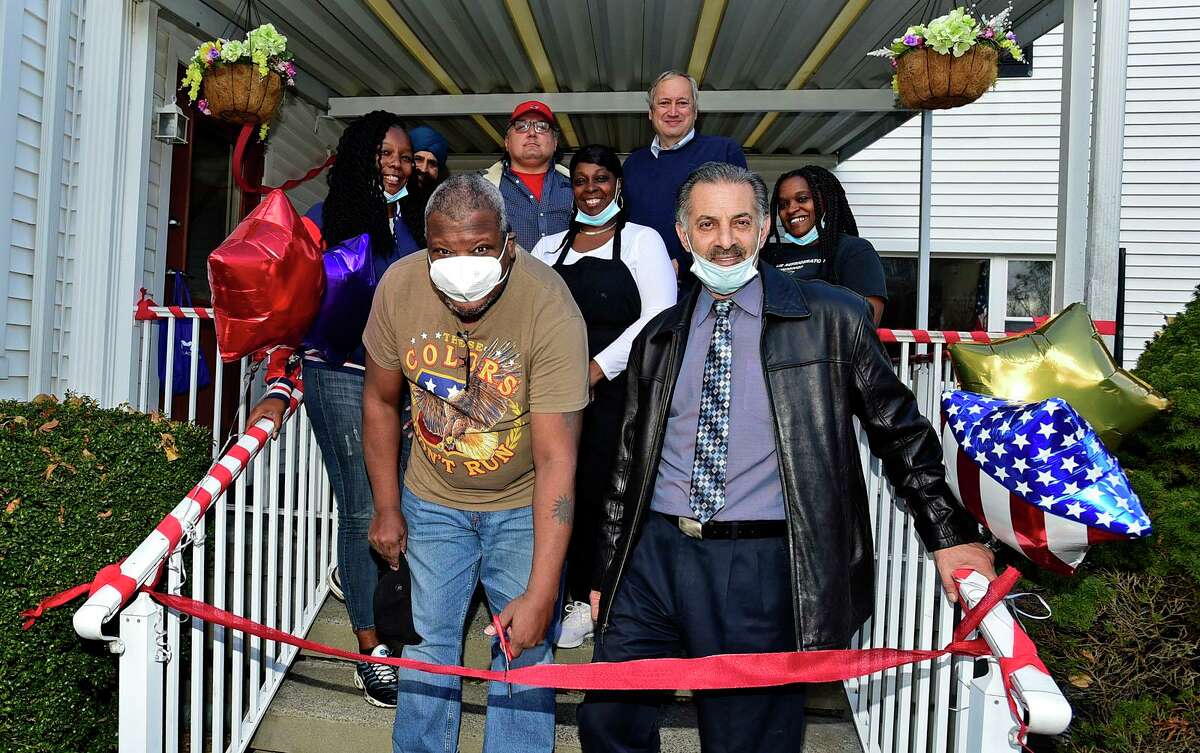 Resident Stanford Adams and Syed Reza, owner of Nelson Place, cut the ribbon at the grand opening ceremony Tuesday, November23, 2021 on Nelson Avenue in Norwalk, Conn. The assisted living facility formerly known as Carlson Place, which was closed due to the living conditions and treatment of residents, is reopening with new ownership and a new name at the same location.