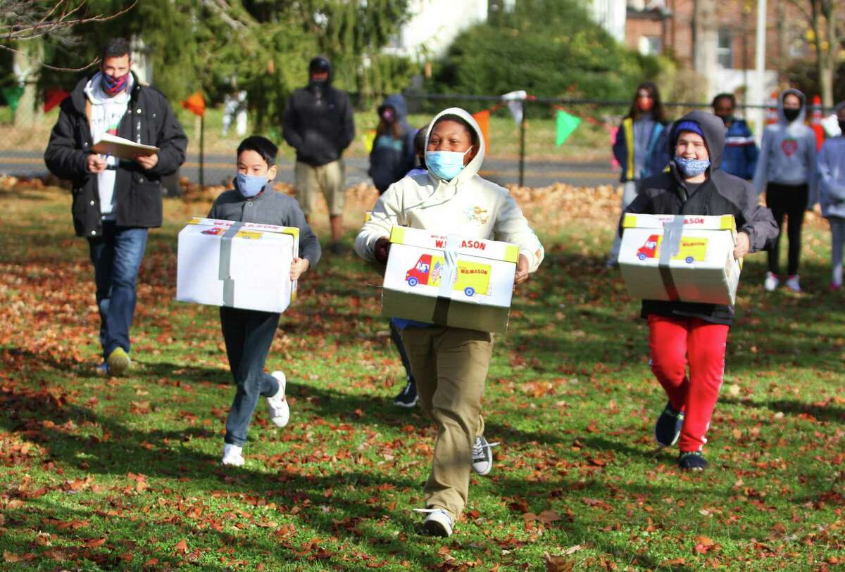 Running with a 20 pound box of copier paper, sixth grade student Nickoy Graham, 11, pulls ahead as he competes in the Atlas Stones event at Strawberry Hill School's Olympic Games in Stamford, Conn., on Tuesday November 23, 2021. The games are a reenactment of the first Olympics and the culminating event after learning different topics related to the ancient Greeks. The students took part in Olympic style competitions with events such as discus, shot put, an academic challenge, atlas stone races, push-up and a dead hang challenge.