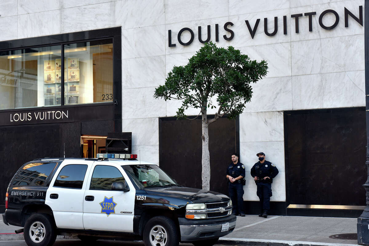 Police stand watch outside the boarded up windows of the Louis Vuitton store in San Francisco's Union Square, on Tuesday, Nov. 23, 2021.