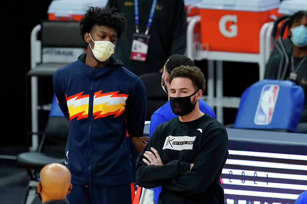 Injured Golden State Warriors center James Wiseman, left, and guard Klay Thompson watch against the Boston Celtics during an NBA basketball game in San Francisco.