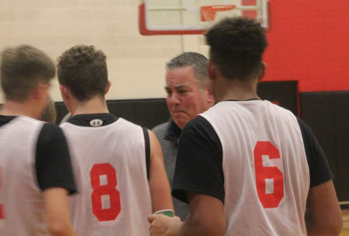 Steve Ernst (second from right) talks with his Reed City basketball team on Monday after a scrimmage.