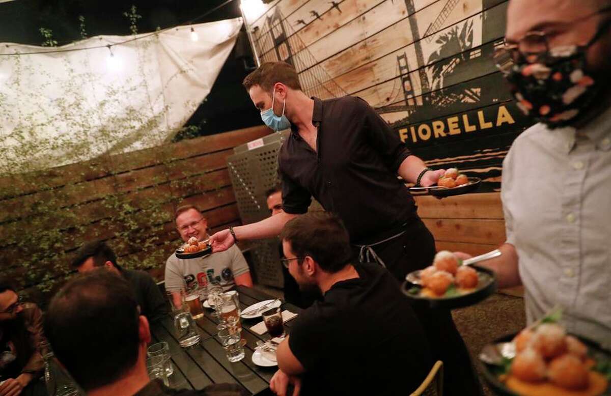 Evan Bachteal (center) serves appetizers during a private event at Fiorella Clement in San Francisco.