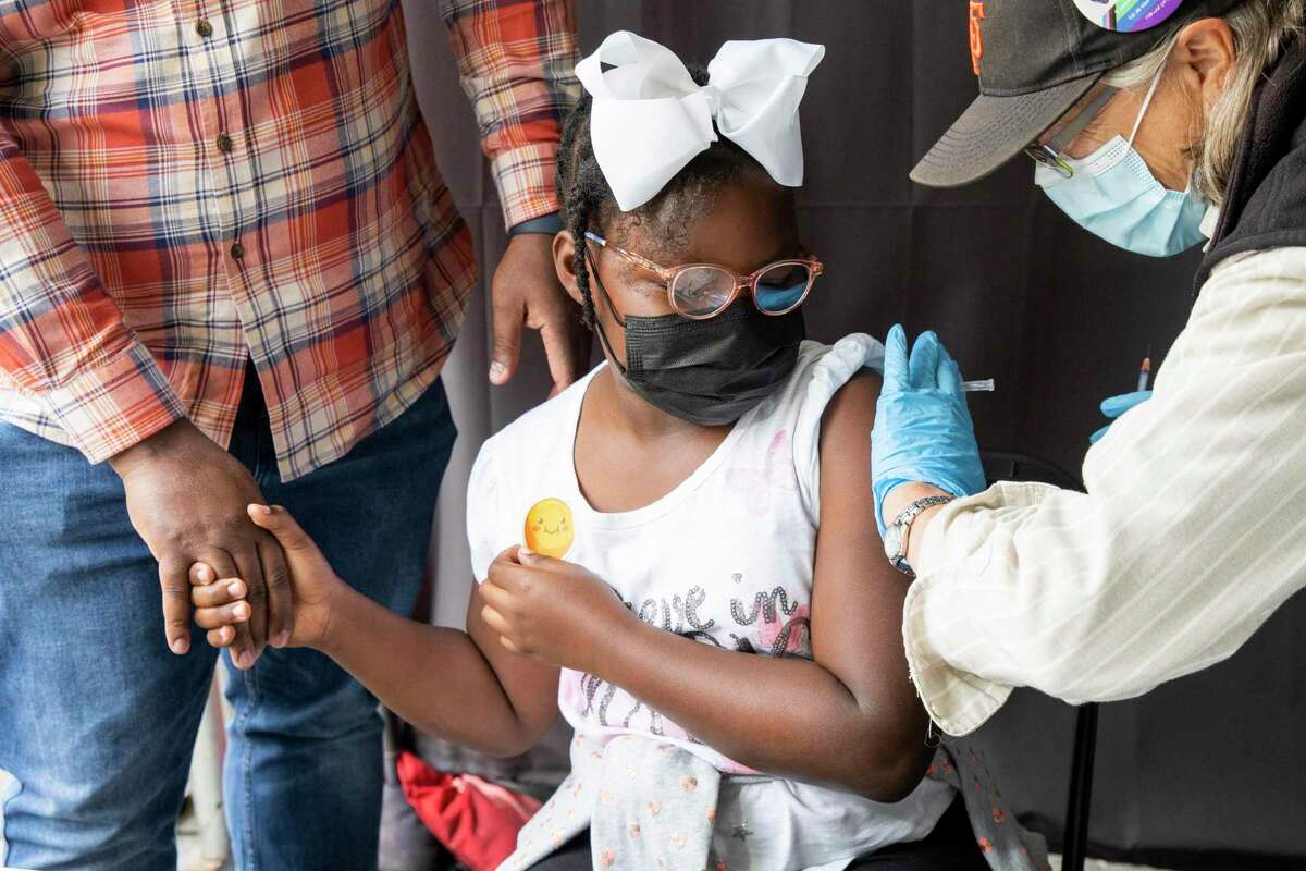 Gianna Shand, 8, accompanied by her father Lloyd Shand, receives a COVID-19 inoculation at the neighborhood vaccination site in San Francisco’s Excelsior District on Nov. 6, shortly after children 5-11 became eligible for the Pfizer-BioNTech vaccine.