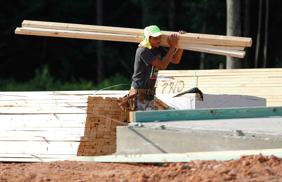 A man moves wood for framing as home construction continues in The Woodlands Hill residential community, Thursday, Aug. 5, 2021, in Willis.
