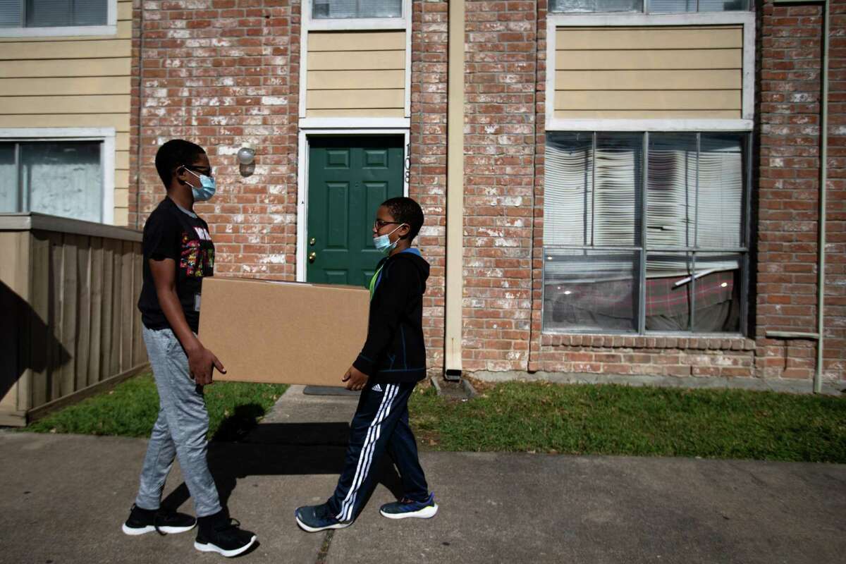 Robby Whitfield, 11, and his brother Myles Whitfield, 8, deliver a box of food to the home of a newcomer Afghan family on Tuesday, Nov. 23, 2021, in Houston. The food was provided by Interfaith Ministries for Greater Houston and Comcast.