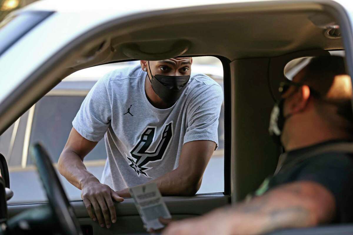 San Antonio Spurs guard Devin Vassell speaks with Robert Serna during a drive-through Thanksgiving dinner event at the West Side Frank Garrett Center, Tuesday, Nov. 23, 2021. Two hundred families were given a complete dinner to cook at home. Spurs Gives, H-E-B and the San Antonio Food Bank hosted the drive-through event. Other Spurs players on hand were Derrick White, Bryn Forbes, Keldon Johnson, Zack Collins and Dejounte Murray.