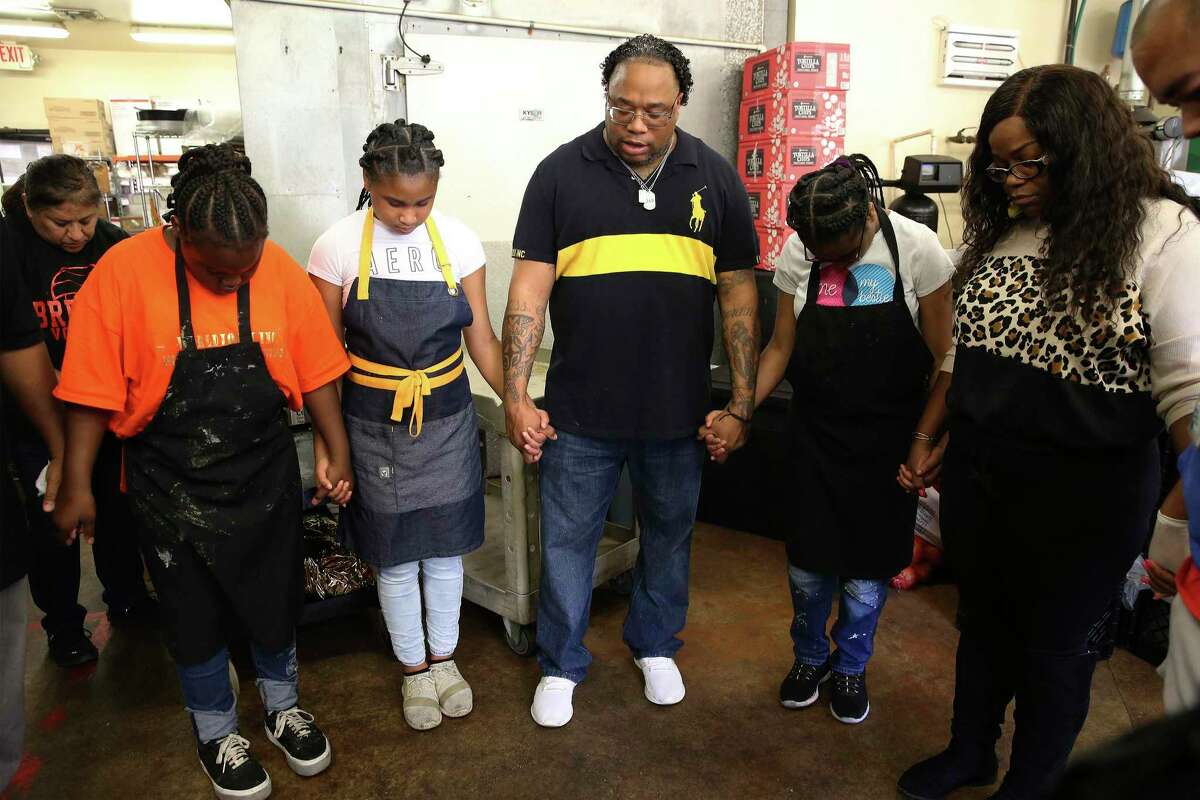 Chef Milas Williams (center) leads a prayer before departing to deliver Thanksgiving meals on Monday. Volunteers with his nonprofit, World Lolei, recently cooked and delivered Thanksgiving dinners to families in need of help across San Antonio. For the past six years, Williams has hosted his annual Youth Empowerment Thanksgiving Dinner, with all of the meals cooked by junior chefs and delivered by volunteers.
