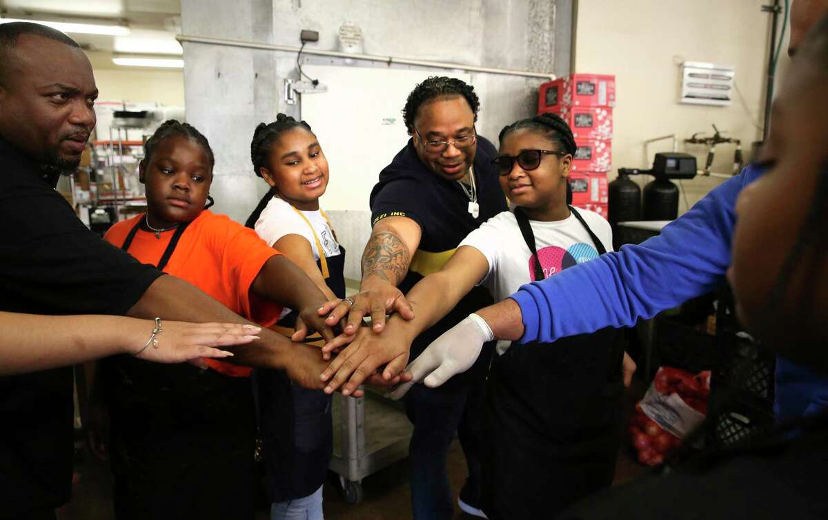 Chef Milas Williams (center) and his volunteers put their hands together before departing to deliver Thanksgiving meals on Monday. Volunteers with his nonprofit, World Lolei, recently cooked and delivered Thanksgiving dinners to families in need of help across San Antonio. For the past six years, Williams has hosted his annual Youth Empowerment Thanksgiving Dinner, with all of the meals cooked by junior chefs and delivered by volunteers.