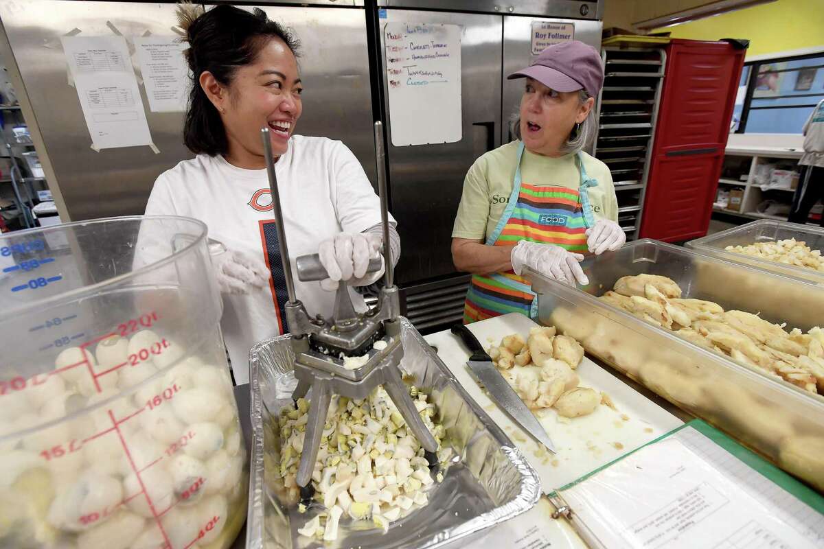 Cathy Hart (left), a volunteer with Houston's Theragood Deeds organization, jokes with Suzanne Lambremonte, whispering, "I'm not very good in the kitchen," while prepping potato salad for Thursday's annual Thanksgiving meal at Some Other Place Wednesday morning. Theragood Deeds volunteered to help with the final preparations, working alongside Some Other Place's usual crew of volunteers from St. Stephen's Episcopal Church. Photo made Wednesday, November 24, 2021 Kim Brent/The Enterprise