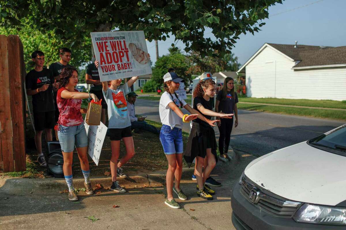 Teenagers from a church group try to stop a car as it enters the Trust Women clinic.