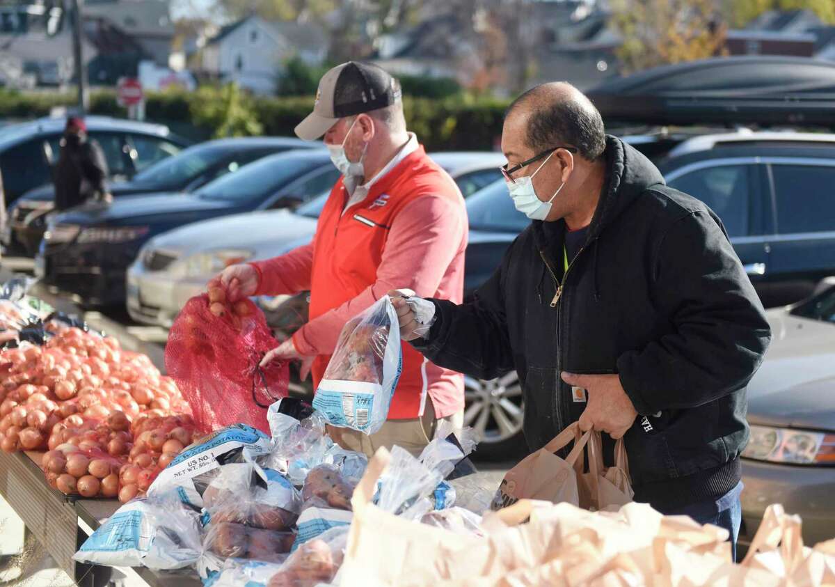 Stratford's Jorge Reyes, right, picks up a Thanksgiving meal as Brad Westbrook volunteers at Smilow Life Center in Norwalk, Conn. Tuesday, Nov. 23, 2021. Norwalk-based Open Doors shelter distributed Thanksgiving turkey or ham meal baskets to 125 local families in need in a grab-and-go format Tuesday at Smilow Life Center.