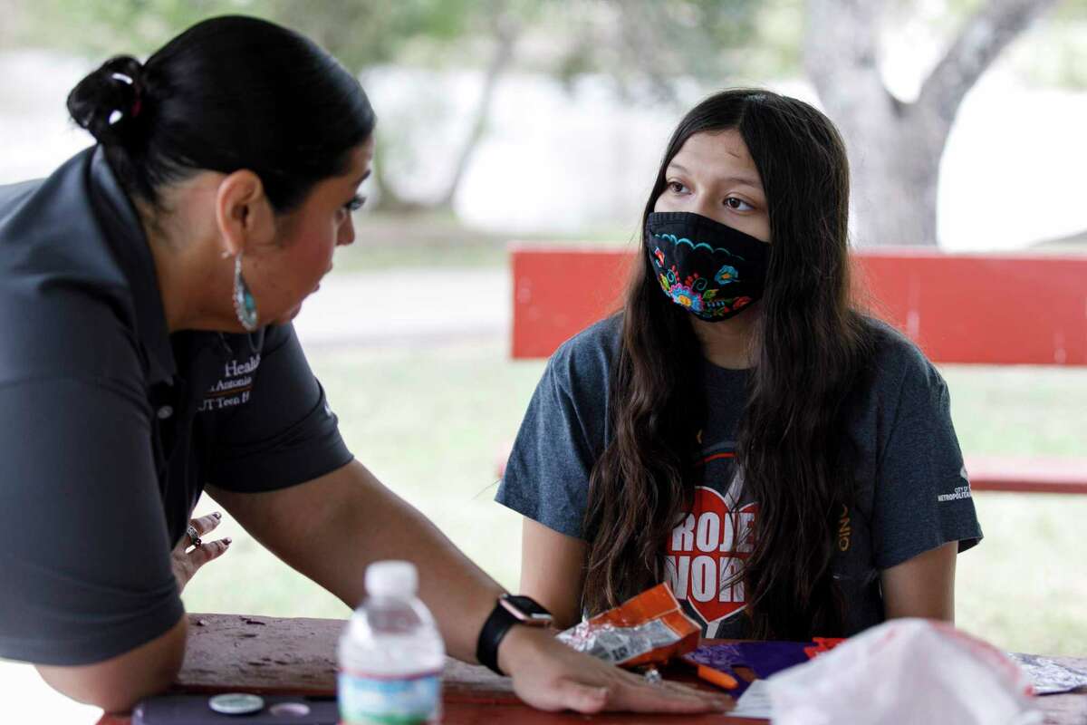 Ambar Rios, a UT Health licensed counselor, talks to Luna Montez, 14, at right, as other teens explore the Project Youth Empowerment and Support modules on their phones during a weekend Project Worth Teen Ambassador meet-up at Southside Lions Park.