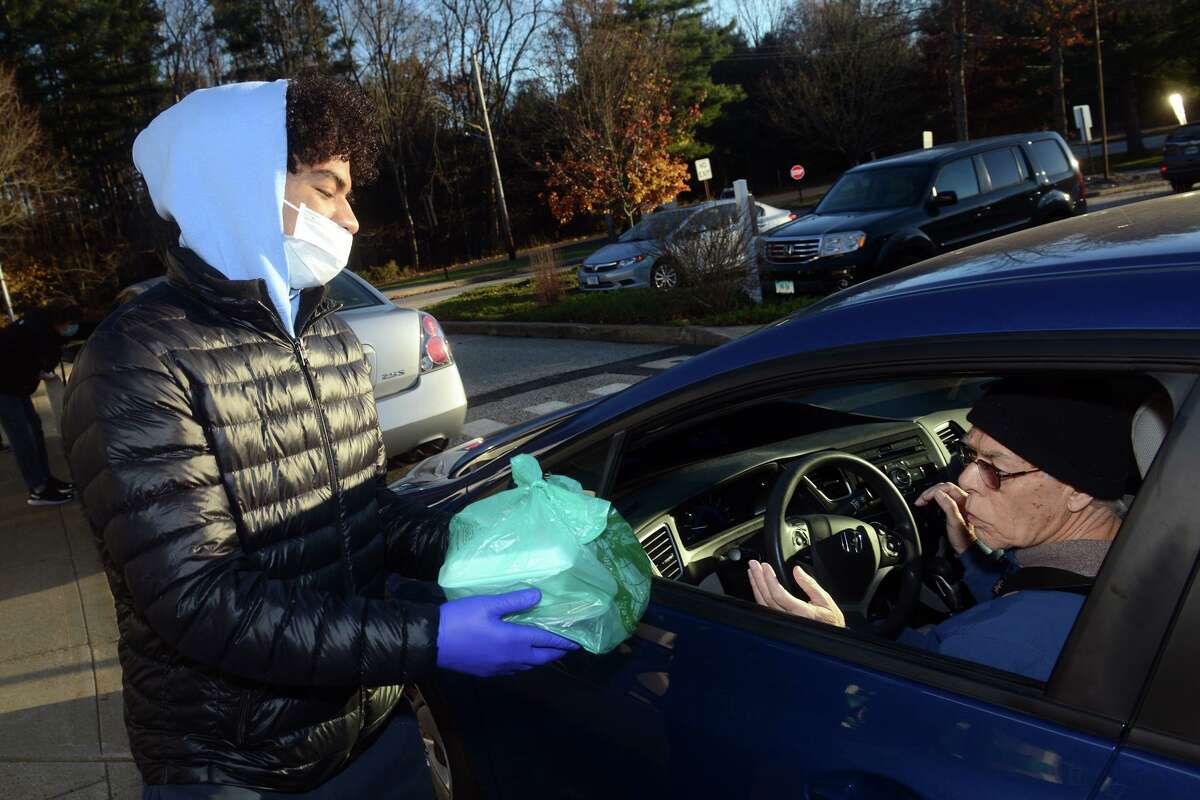 Siomar Rodriguez, from the Boys & Girls Club of Shelton, delivers a Thanksgiving meal to a waiting driver during the drive-thru pickup in front of the Shelton Senior Center on Wednesday.