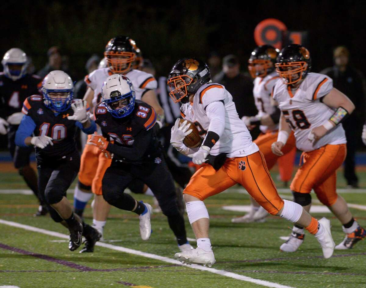 Ridgefield’s Ignacio Brina (9) cuts past Danbury’s Marcos Rodriguez (10) and Will Gordon (32) on his way to scoring a touchdown in the football game between Ridgefield and Danbury high schools, on Wednesday at Danbury High School. Ridgefield won 13-8.