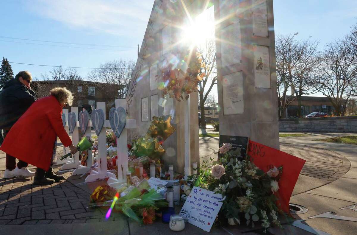 A woman lays flowers at a memorial in Waukesha, Wis., on Tuesday near where people attending a Christmas parade were hit and killed by driver.