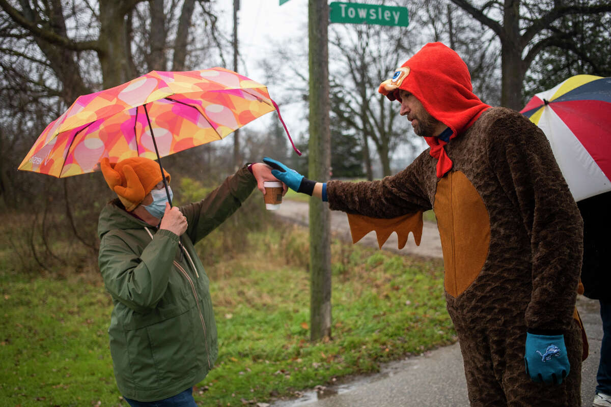 Peter Buist gives high-fives and hugs to participants of the annual Thanksgiving Day Turkey Trot Thursday, Nov. 25, 2021 at the Tridge in downtown Midland. (Katy Kildee/Midland Daily News)