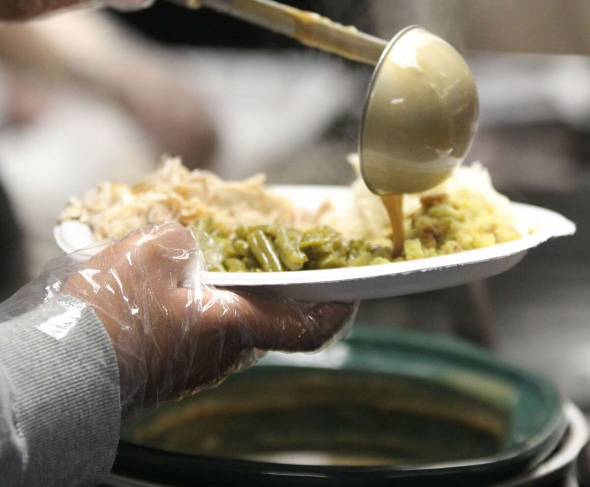 Gravy is added to a plate by a volunteer server at a Thanksgiving dinner last year at the Salvation Army's Alton Corps Community Center. Proper food safety ensures a safe holiday.