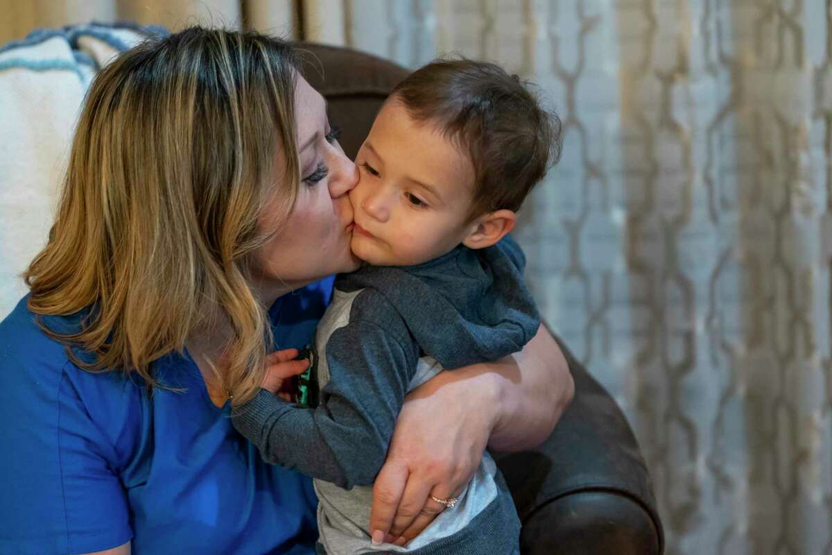 Valerie Villegas kisses her youngest son, Nicholas, 2, in her home, Thursday, Nov. 18, 2021, in Portland, TX. The mother of six lost her husband, Robert Villegas, in January after a three-week-long battle with Covid. Villegas, who was an accomplished martial artist and had been working as a truck driver, was in good health until he contracted Covid. Now Villegas, who works as a hospice nurse, is adjusting to life raising her five boys and one daughter who is in her first year of college on her own.