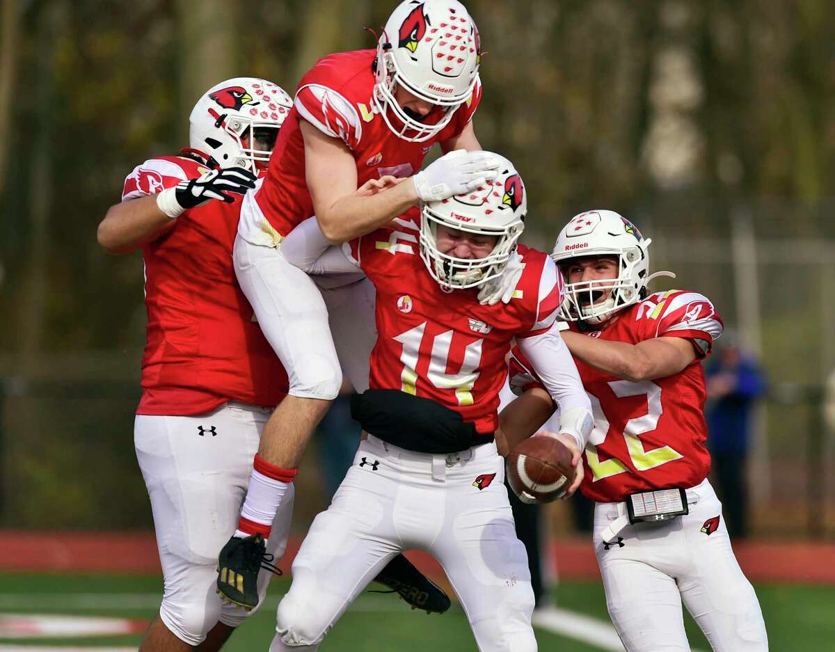 Teammates celebrate with Greenwich QB Jack Wilson (14) after scoring a touchdown against Staples on Thanksgiving Day. Athletic directors were happy to see the return of Thanksgiving games, not only for the players’ and fans’ sake but also because of the revenue created.