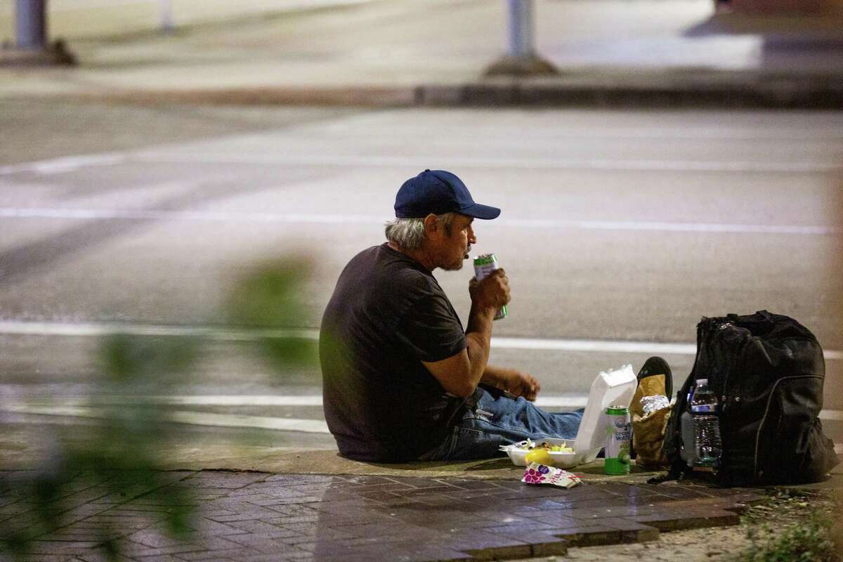 A man eats a dinner provided by the Food Not Bombs near the Houston Public Library - Central Library, Wednesday, Oct. 20, 2021, in Houston.
