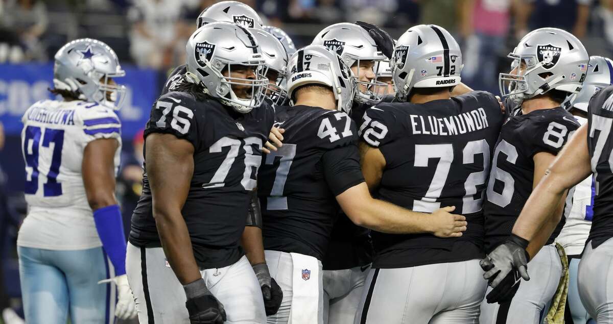 Dallas Cowboys defensive tackle Osa Odighizuwa (97) walks past as Las Vegas Raiders' John Simpson (76), Trent Sieg (47), Jermaine Eluemunor (72) and Daniel Helm (86) celebrate with Daniel Carlson, center smiling, after Carlson kicked a game-winning field goal in overtime of an NFL football game against the Dallas Cowboys in Arlington, Texas, Thursday, Nov. 25, 2021. (AP Photo/Michael Ainsworth)
