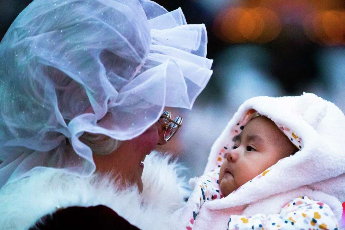 Six-month old Emily Yosephine Vásquez Chuc observes Mrs. Claus while the iconic woman holds her at the 33rd Annual Uptown Holiday Lighting, Thursday, Nov. 25, 2021, in Houston.