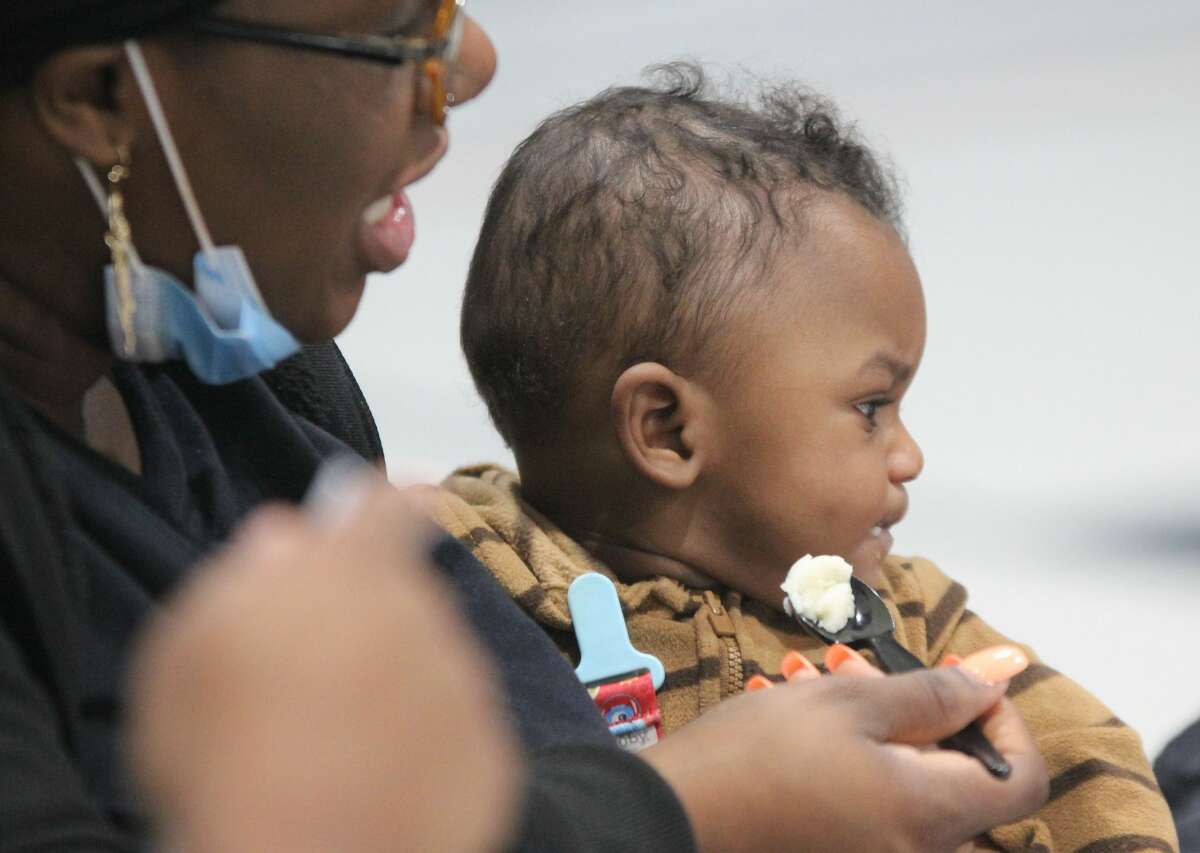 Rose Thomas tries to persuade her distracted grandson, Amir Smith, 7 months, to eat some mashed potatoes at a Thanksgiving dinner Wednesday at the Salvation Army's Alton Corps Community Center. The annual dinner is put on by Abundant Life Church.