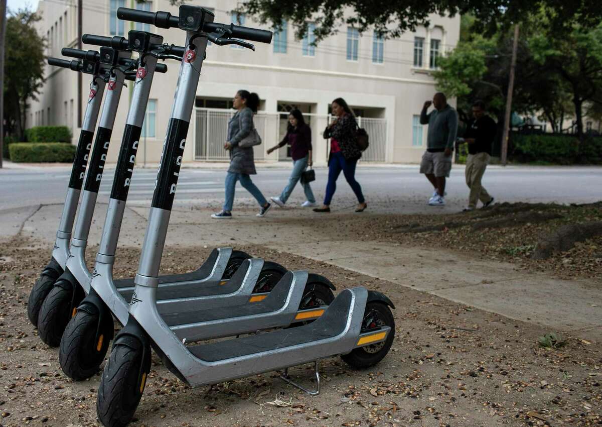 People walk past a row of electric Bird scooters along Avenue E and 4th Street in downtown San Antonio last week. Ridership is still down from pre-pandemic peaks as the industry tries to find its niche among micro-mobility options.