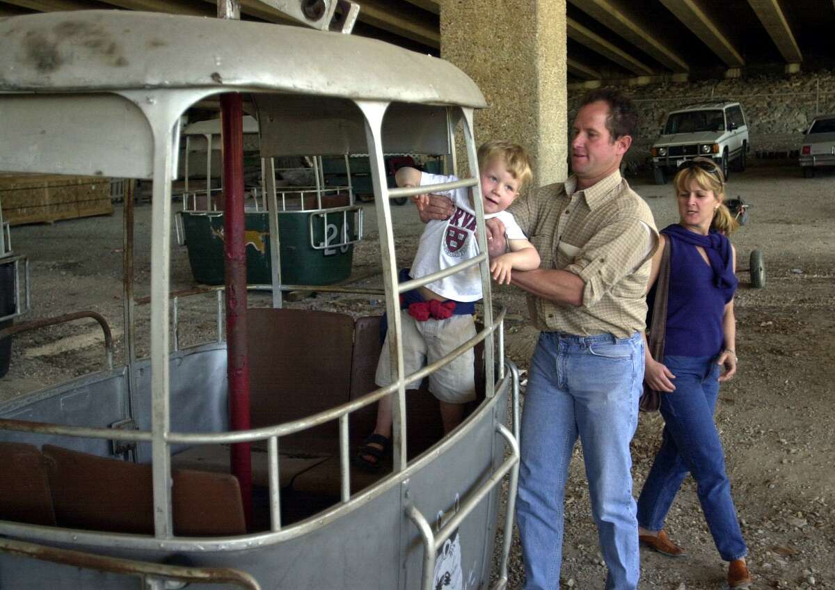 Sur cette photo de 2002, le développeur de San Antonio, Mitch Meyer, aide son fils Dan, alors âgé de 4 ans, à monter à bord d'une des télécabines du zoo de San Antonio lors de la vente des télécabines du sky ride de Brackenridge Park.  Les gondoles ont été vendues 1 000 $ chacune pour amasser des fonds pour le zoo.  La femme de Mitch, Susan, est à droite.  Mitch a acheté 10 des gondoles.