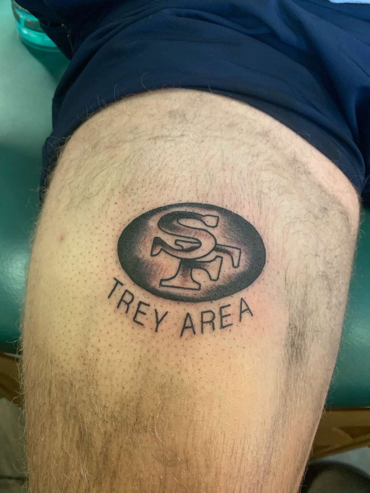 A close-up shot of Christian Coelho's "Trey Area" tattoo.