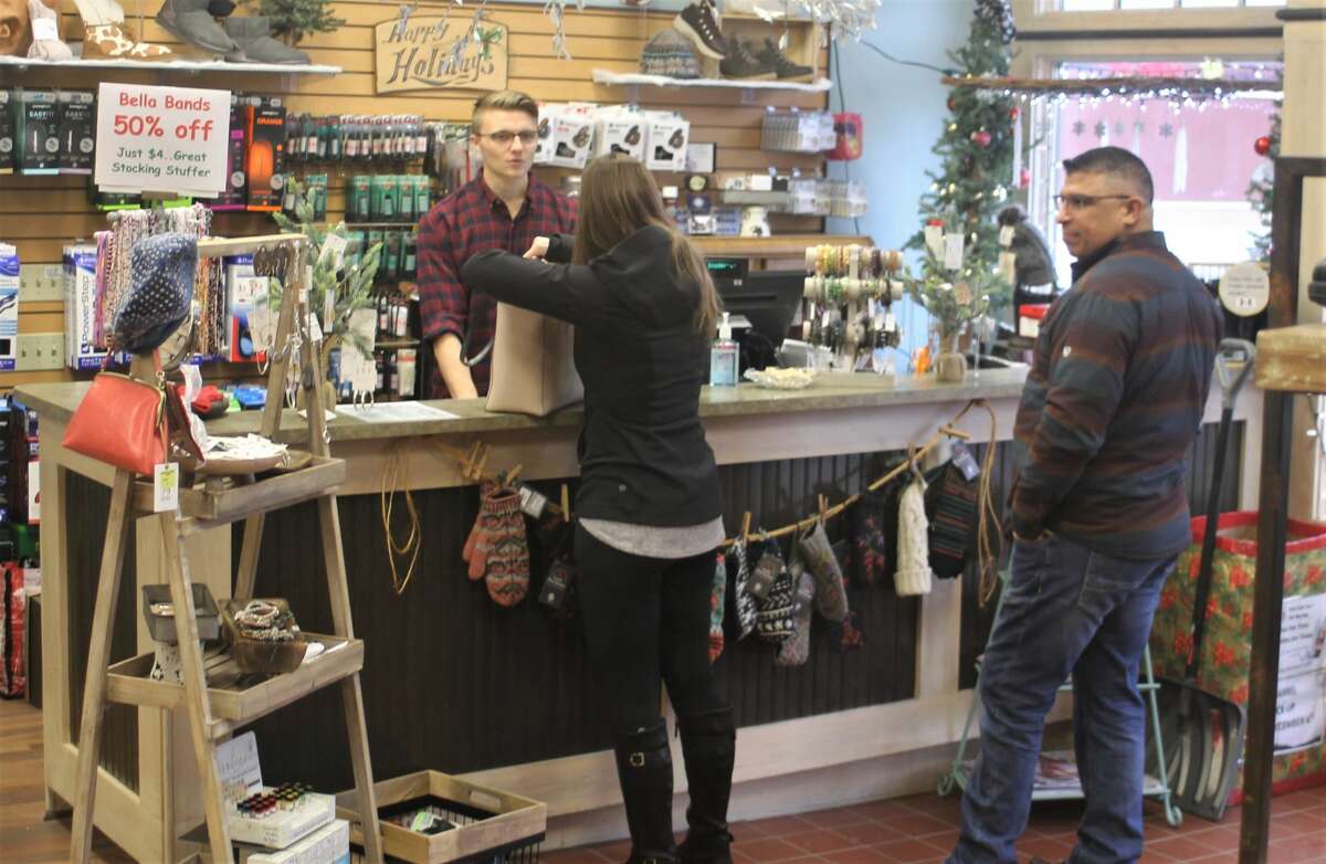 Cashier Noah Owens rings up a customer at Snyder's Shoes in Manistee on Friday.