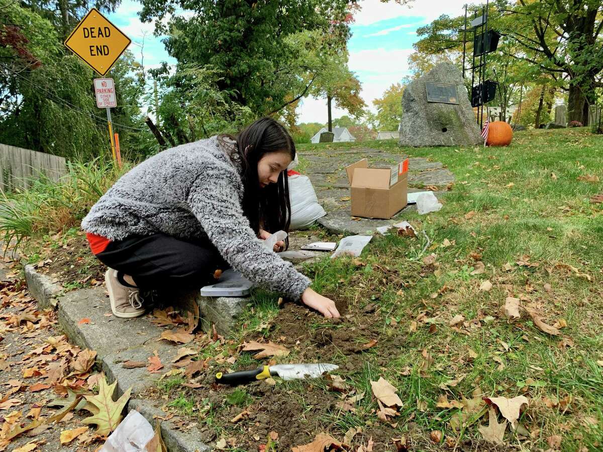 Grace Popp works to plant flowers at Byram Cemetery.