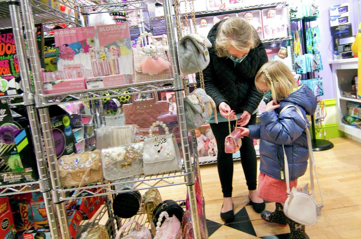 Whitney Milligan, 4, of Stamford, show her mom Molly what she wants for the holidays while the family shops at Funky Monkey toy store in Greenwich, Conn., on Friday November 26, 2021.