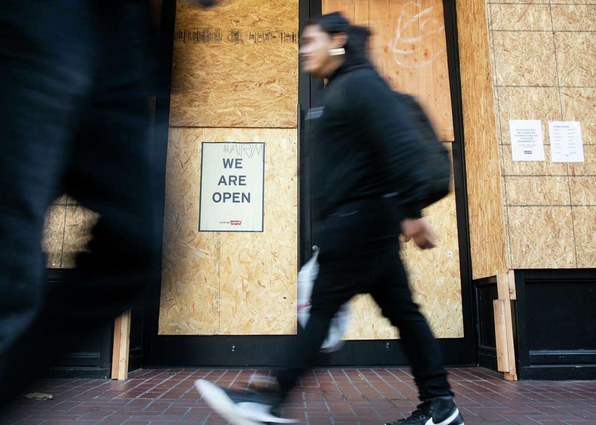 Shoppers pass a boarded up Levi’s store open for business on Black Friday at Union Square in San Francisco.