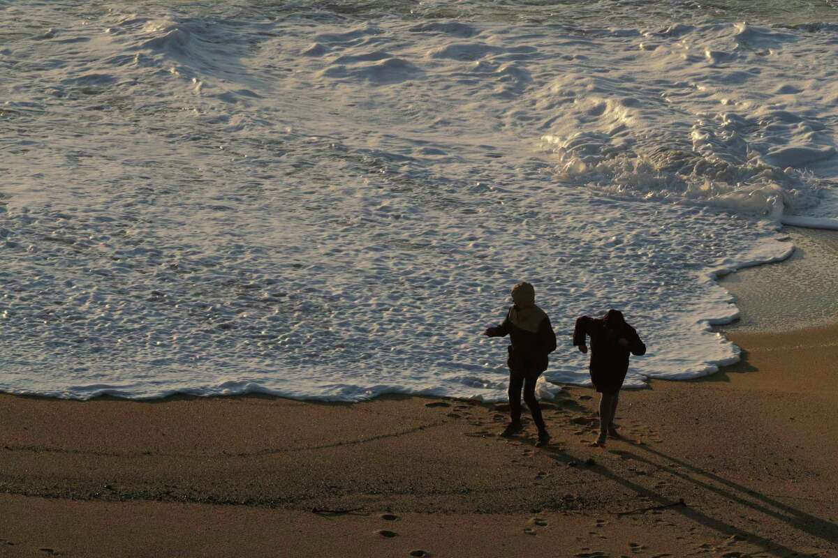 Visitors walk along Cowell Ranch Beach outside Half Moon Bay, Calif., on Feb. 24, 2021, near where a 12-year-old boy was swept out to sea after he was hit by a sneaker wave earlier this year.