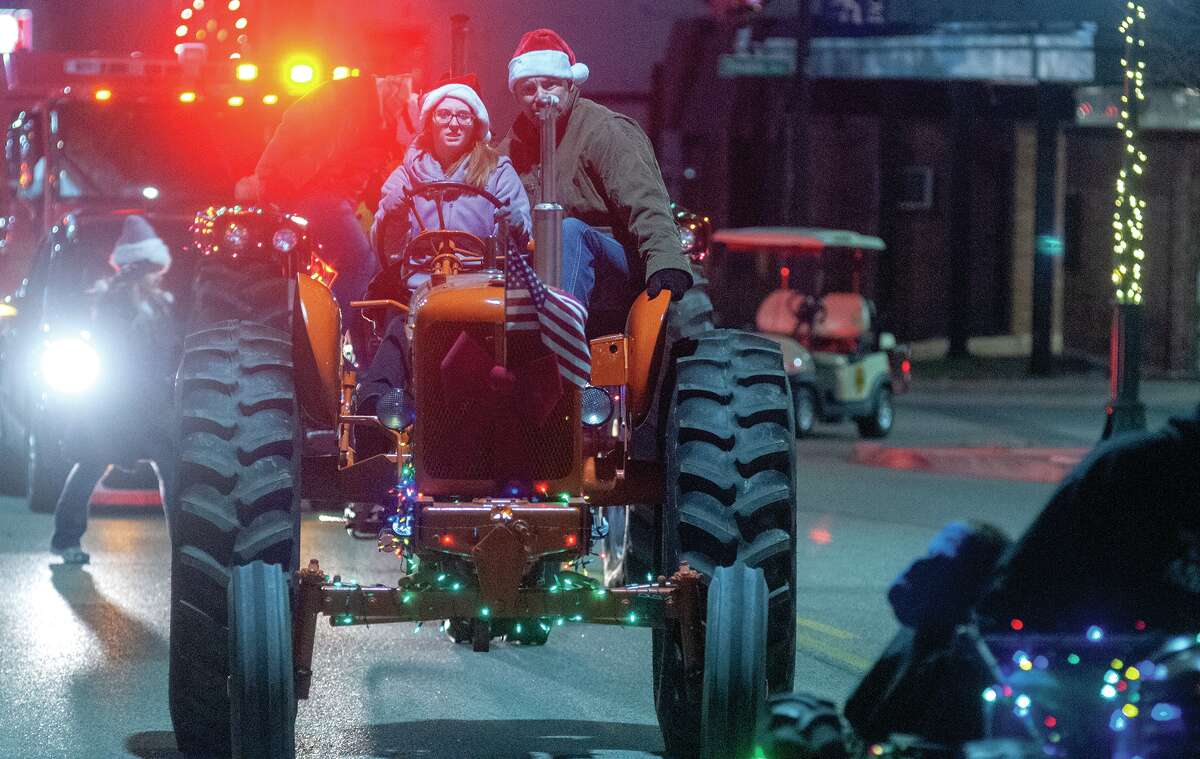 Brooke McCurry (left) and Justin Kirk participate Friday in the annual Christmas parade in downtown Jacksonville. The parade, which drew a crowd that packed the downtown square, made two loops around the square before finishing up with distanced but in-person greetings from Santa and Mrs. Claus.