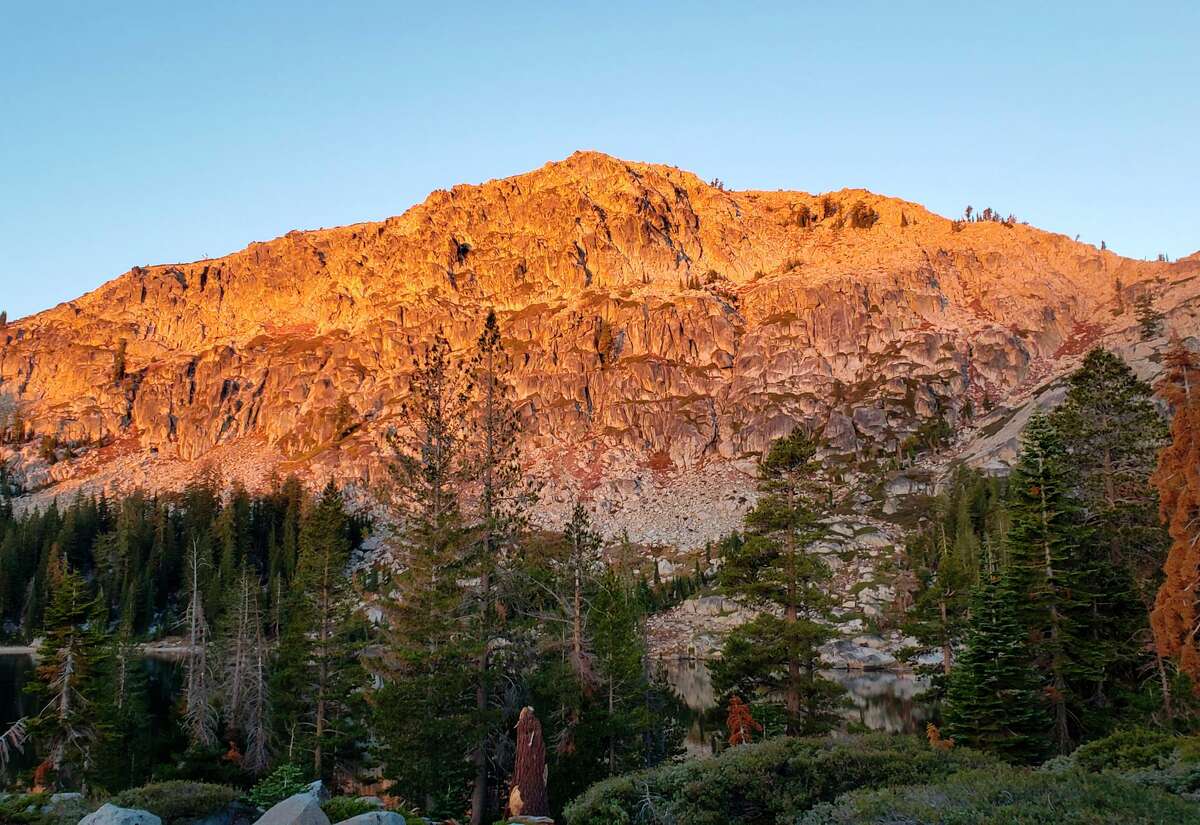 Alpenglow lights up Frog Lake Cliff across the water from the new backcountry huts in the mountains near Truckee.