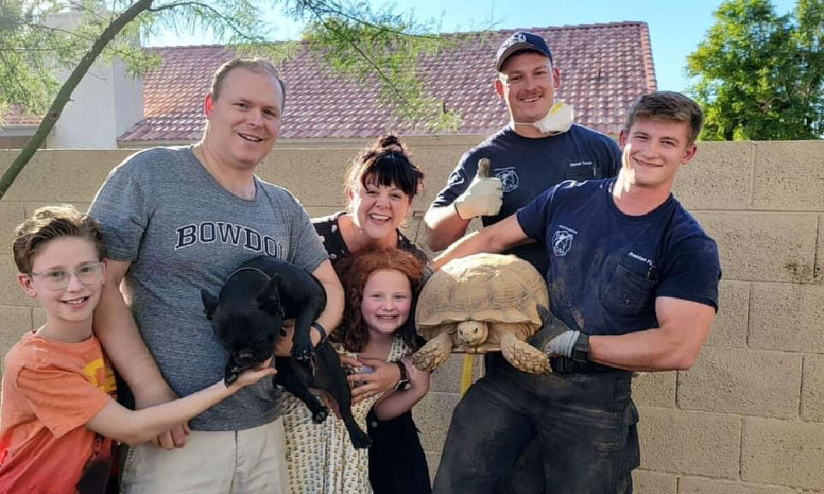 The Fortin family poses with Scottsdale, Ariz., firefighters Derek Owen and Preston Fuller after they rescued the Fortins' pet dog, who ventured into their tortoise's burrow. CREDIT: Courtesy Scottsdale Fire Department