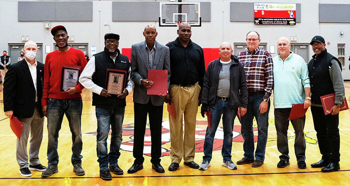With Alton assistant AD Eric Roberson (far left), members of the 1979-80 Redbirds boys basketball team (from left) John 'Main' Smith, Troy Washpun, Chuck Williams, Robin Stockard, Rich Kortkamp, Marcus Renken, Ron Twichell and DeWayne Williams are introduced to the crowd at halftime in Alton's game Wednesday night in Godfrey