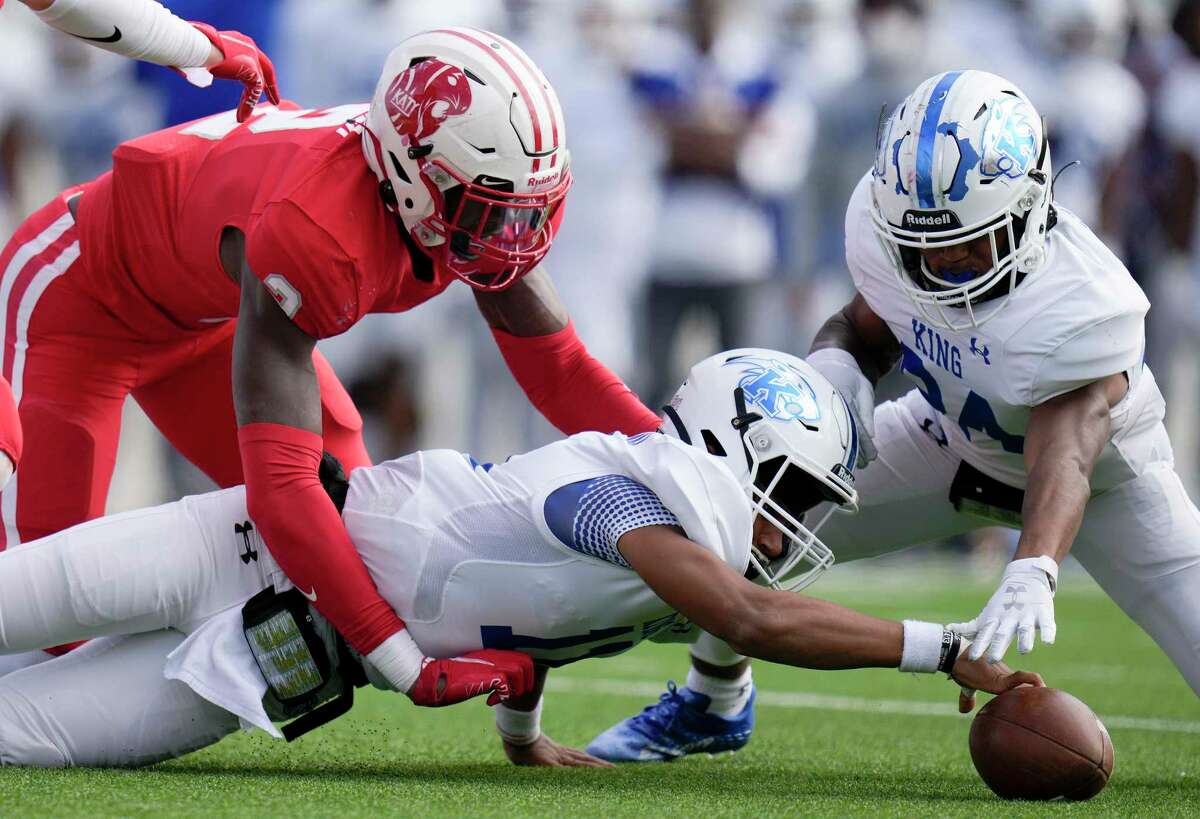 C.E. King quarterback Nehemiah Broussard, bottom, reaches for his fumble after being sacked by Katy defensive lineman Malik Sylla, left, during the first half of a 6A Division II regional semi-final high school football playoff game, Friday, Nov. 26, 2021, in Katy.