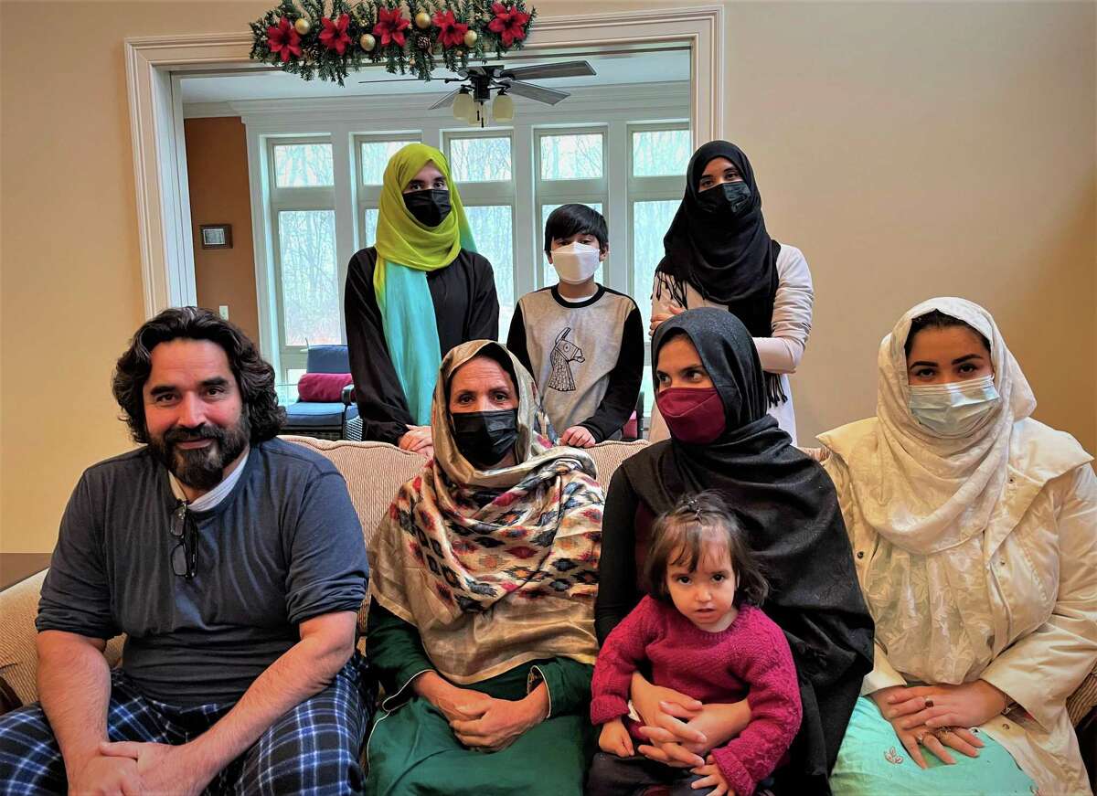 Shamsula Akberzai, left front, sits next to his cousin Laliuma Gharmal, four of her adult daughters, her granddaughter and his son, center back, in his home in Mansfield the day after Thanksgiving. Akberzai immigrated to the United States as a refugee in 1992 and settled in Connecticut. Gharmal and her family just arrived and live in Bridgeport.