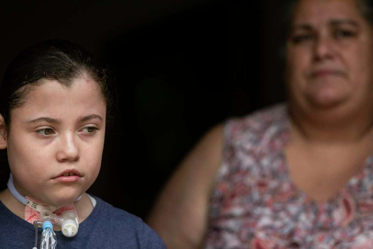 Stephanie Mejia, 11, stands in the doorway of her family's home next to her mother Brenda Slocume. A student at Tafolla Middle School, she went months without speech therapy or homebound classes because of staff shortages and a paperwork error.