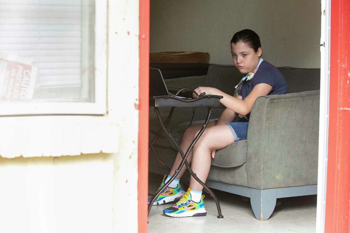 Stephanie Mejia, 11, sits on the couch at home as she looks at school work for the day. A student at Tafolla Middle School, she went months without speech therapy or homebound classes because of staff shortages and a paperwork error.