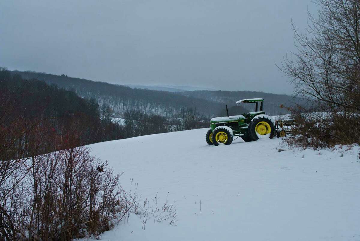 A farm tractor is seen in a snow covered field on Sunday, Nov. 28, 2021, in Austerlitz, N.Y.