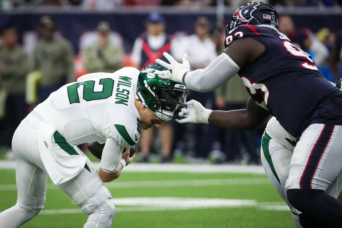 Houston Texans defensive tackle Jaleel Johnson (93) grabs the facemask of New York Jets quarterback Zach Wilson (2) in a sack attempt during the second quarter of an NFL football game Sunday, Nov. 28, 2021 in Houston. Johnson was called for a facemask penalty on the play.