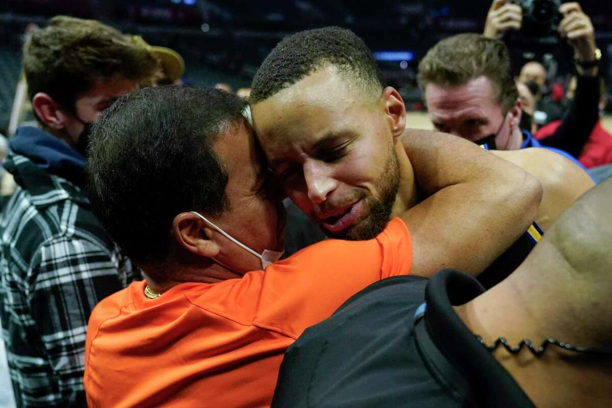 Golden State Warriors guard Stephen Curry, right, gets a hug from a fan after winning an NBA basketball game against the Los Angeles Clippers 105-90 in Los Angeles, Sunday, Nov. 28, 2021. (AP Photo/Ashley Landis)